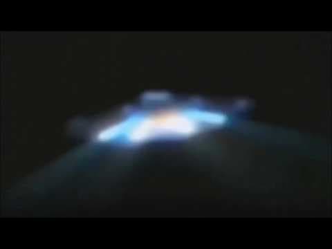 UFO in an open plot emitting light onto the ground nearby